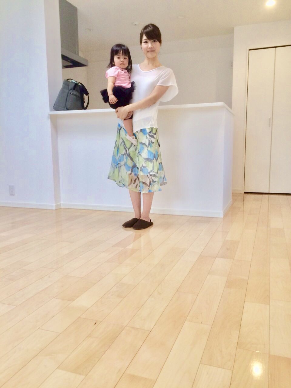 千葉県千葉市美浜区のご新築マンションで施工後のLDKでお子さまを抱くお客様（セラミックガラスフロアコーティング（微光沢）施工後）