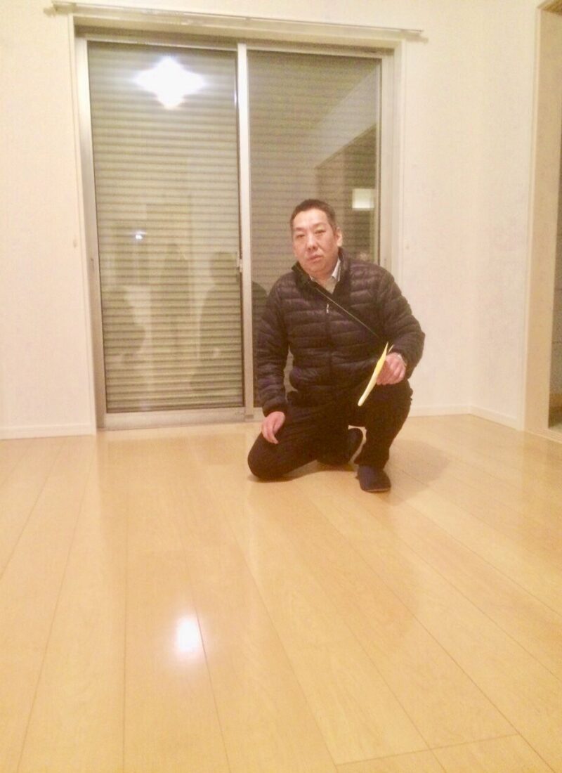 東京都千代田区のご新築マンションで施工後の艶やかな床でしゃがむお客様（セラミックガラスフロアコーティング（微光沢）施工後）