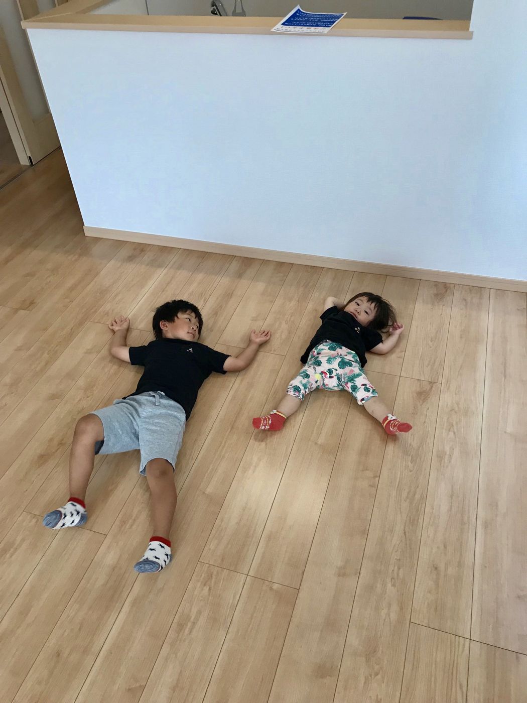 東京都府中市のご新築戸建てで施工後の床に寝ころぶお子さま2人(ガラスフロアコーティング施工後)