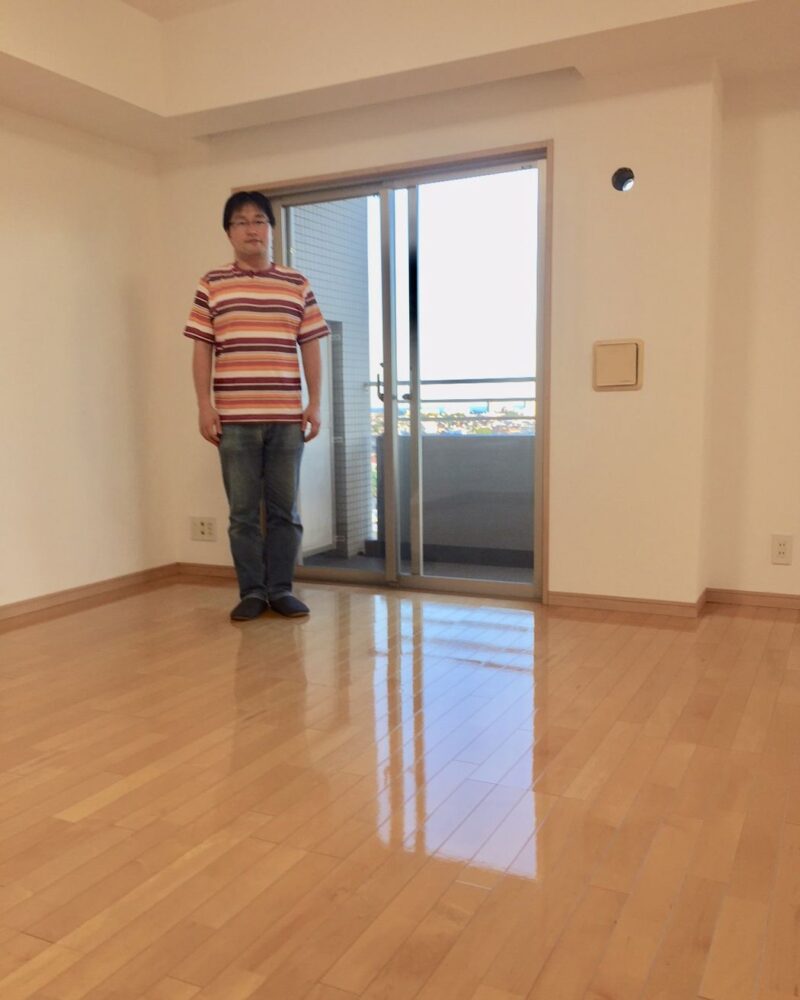 埼玉県さいたま市桜区のリノベーション済みマンション（入居前）で施工後のリビングに立つお客様（セラミックガラスフロアコーティング（微光沢）施工後）