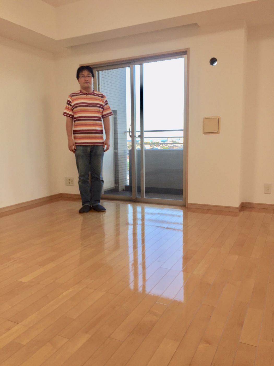 埼玉県さいたま市桜区のリノベーション済みマンション（入居前）で施工後のリビングに立つお客様（セラミックガラスフロアコーティング（微光沢）施工後）