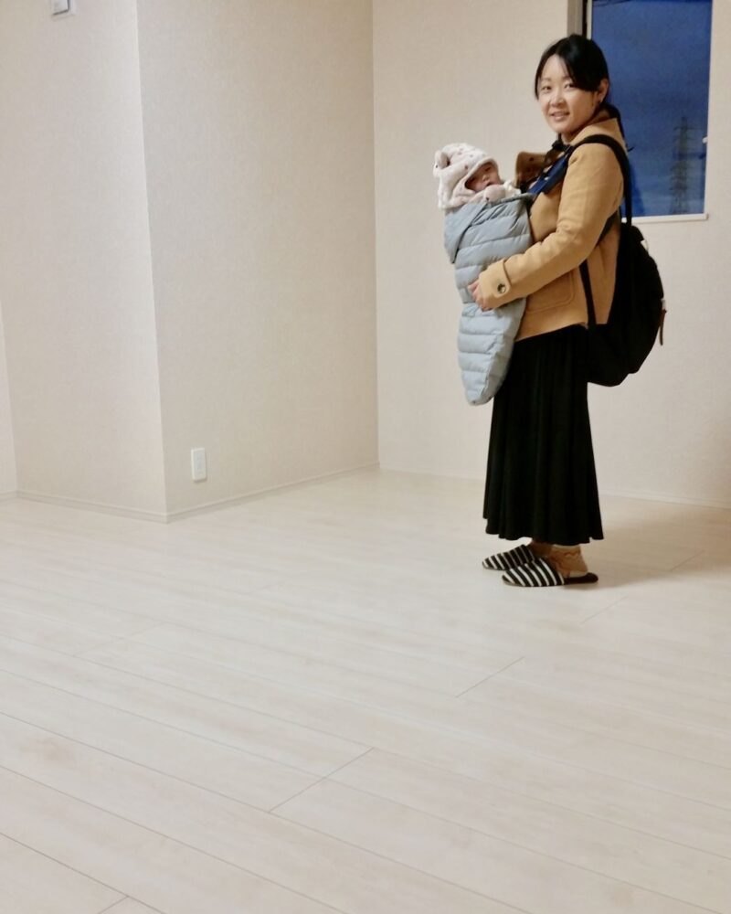 東京都世田谷区のご新築戸建てで施工後の明るい床で赤ちゃんを抱くお客様（ワンニャンすべらんフロアコーティング施工後）