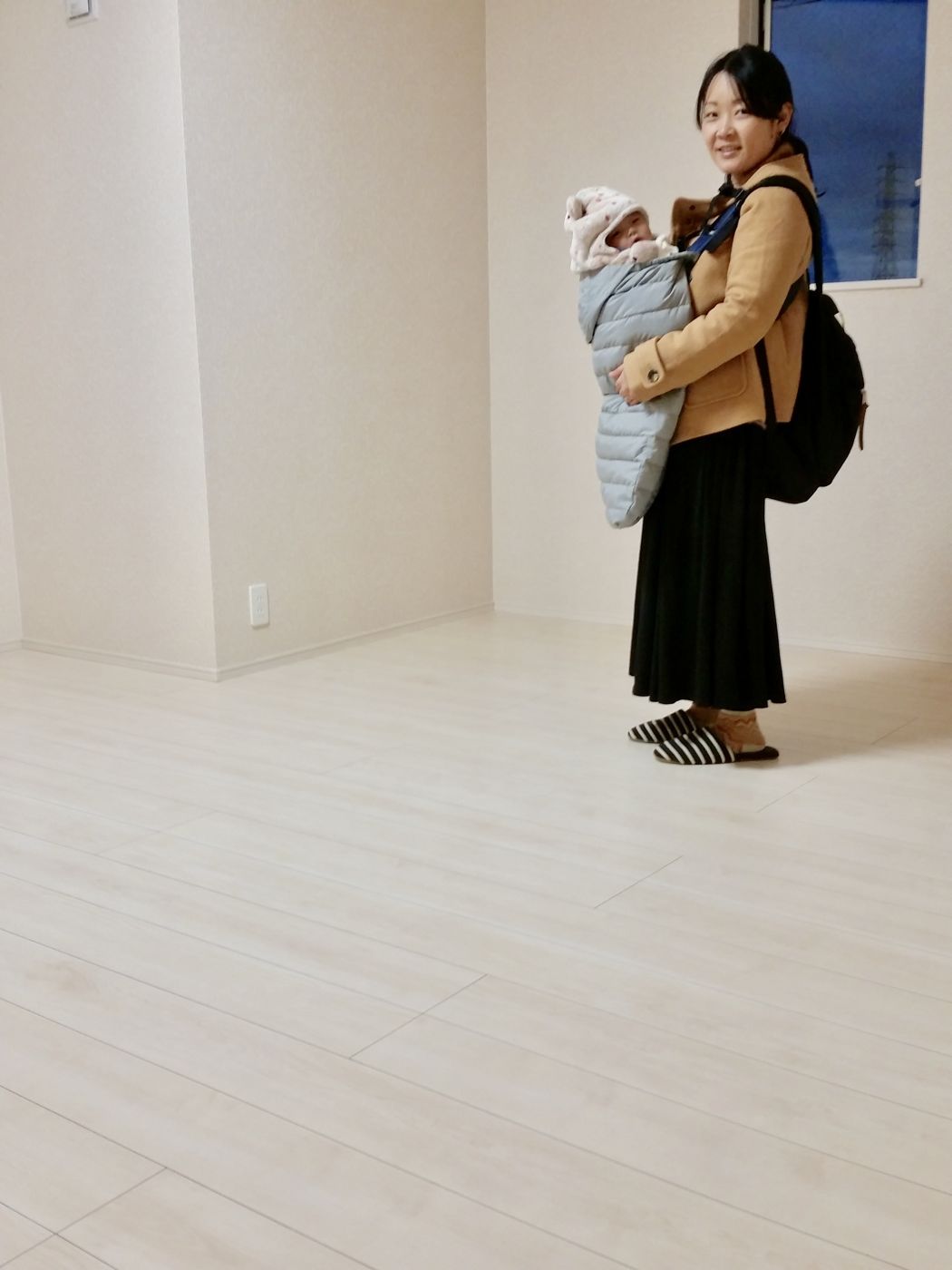 東京都世田谷区のご新築戸建てで施工後の明るい床で赤ちゃんを抱くお客様(ワンニャンすべらんフロアコーティング施工後)