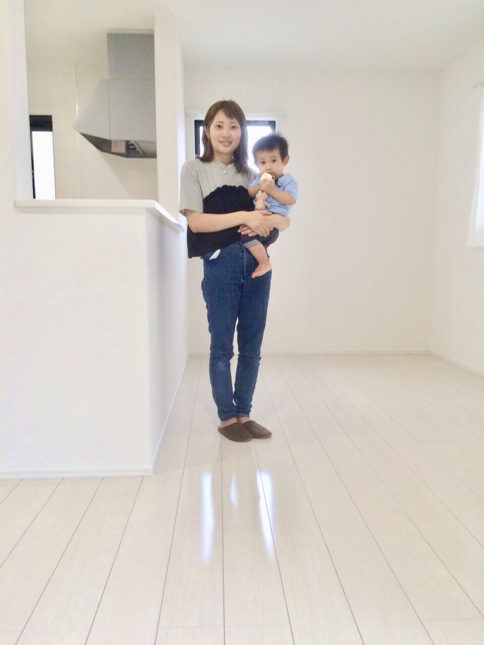 千葉県八街市のご新築戸建てで施工後のLDKでお子さまを抱くお客様(セラミックガラスフロアコーティング(微光沢)施工後)