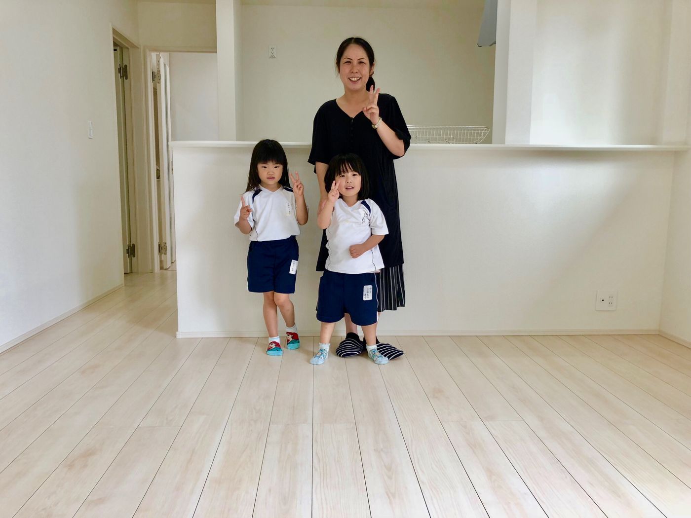 神奈川県横浜市港南区のリノベーション済みマンションで施工後のLDKに立つご家族（ガラスフロアコーティング施工後）